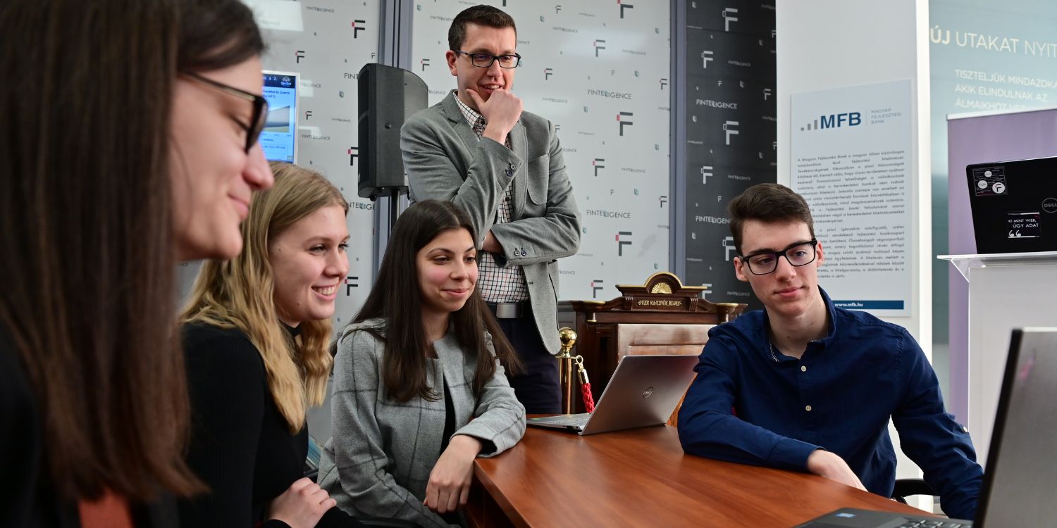 Miskolci Egyetemen oktató és diákok egy laptopot néznek.