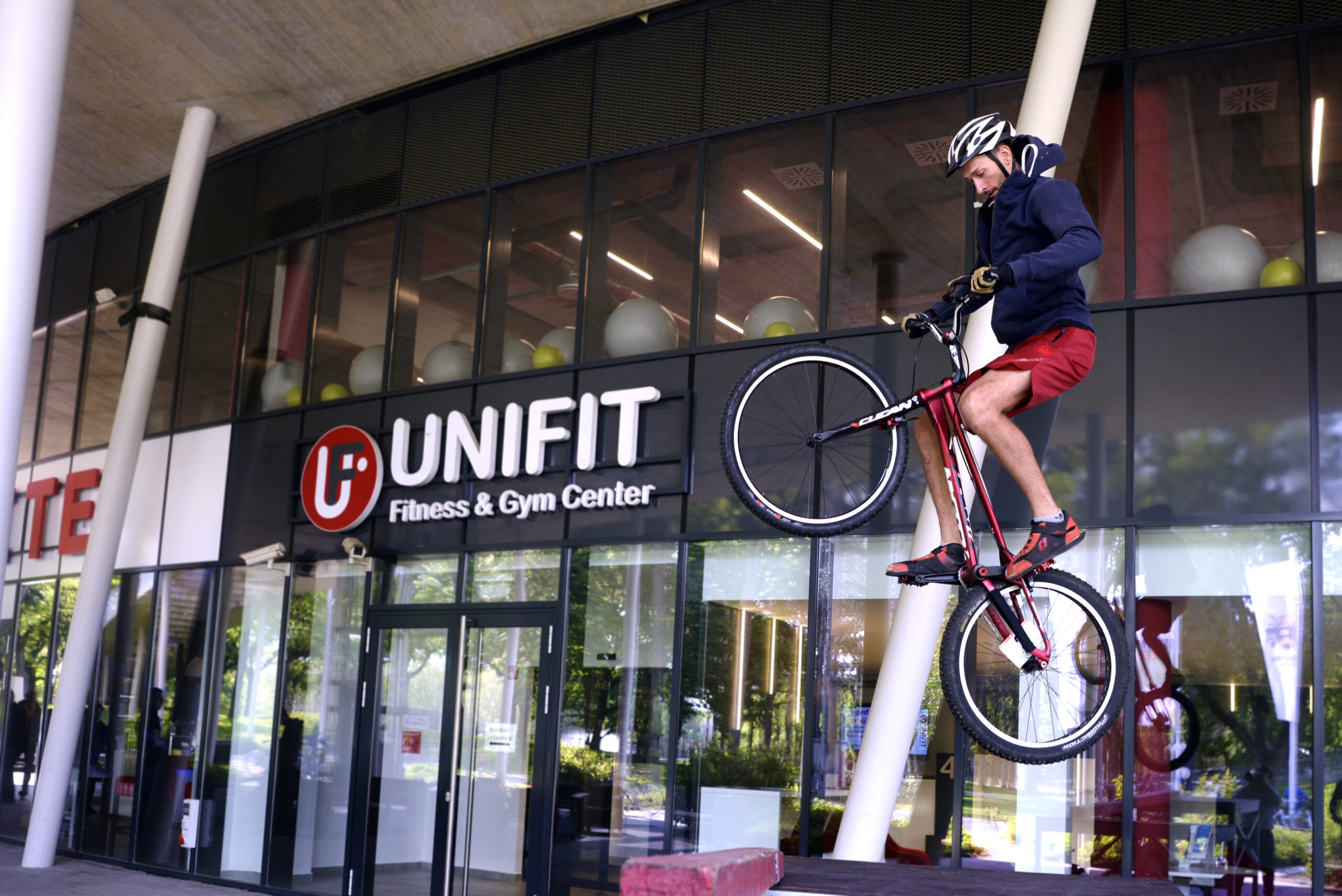 Debreceni Egyetem sportkomplexuma előtt egy biciklis a levegőben van egy ugrás közben.
