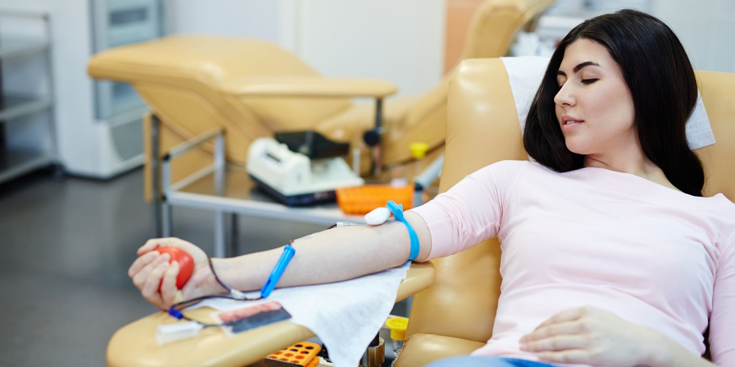 Lány fekszik egy székben és egy labdát nyomkodva vért ad.